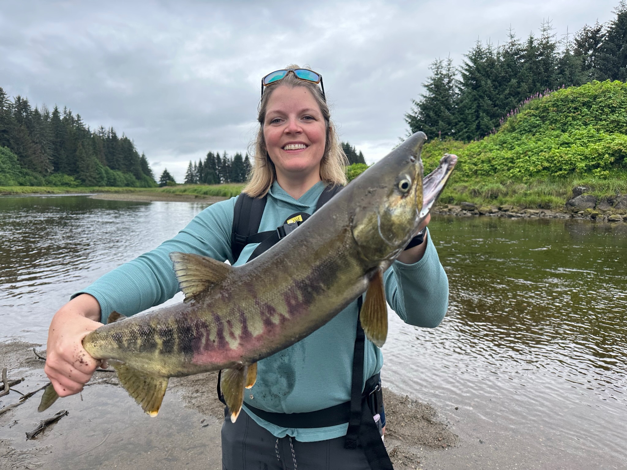 Woman holding salmon in Alaska wilderness